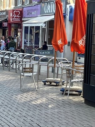Metal barriers in a pedestrianised street area with seating