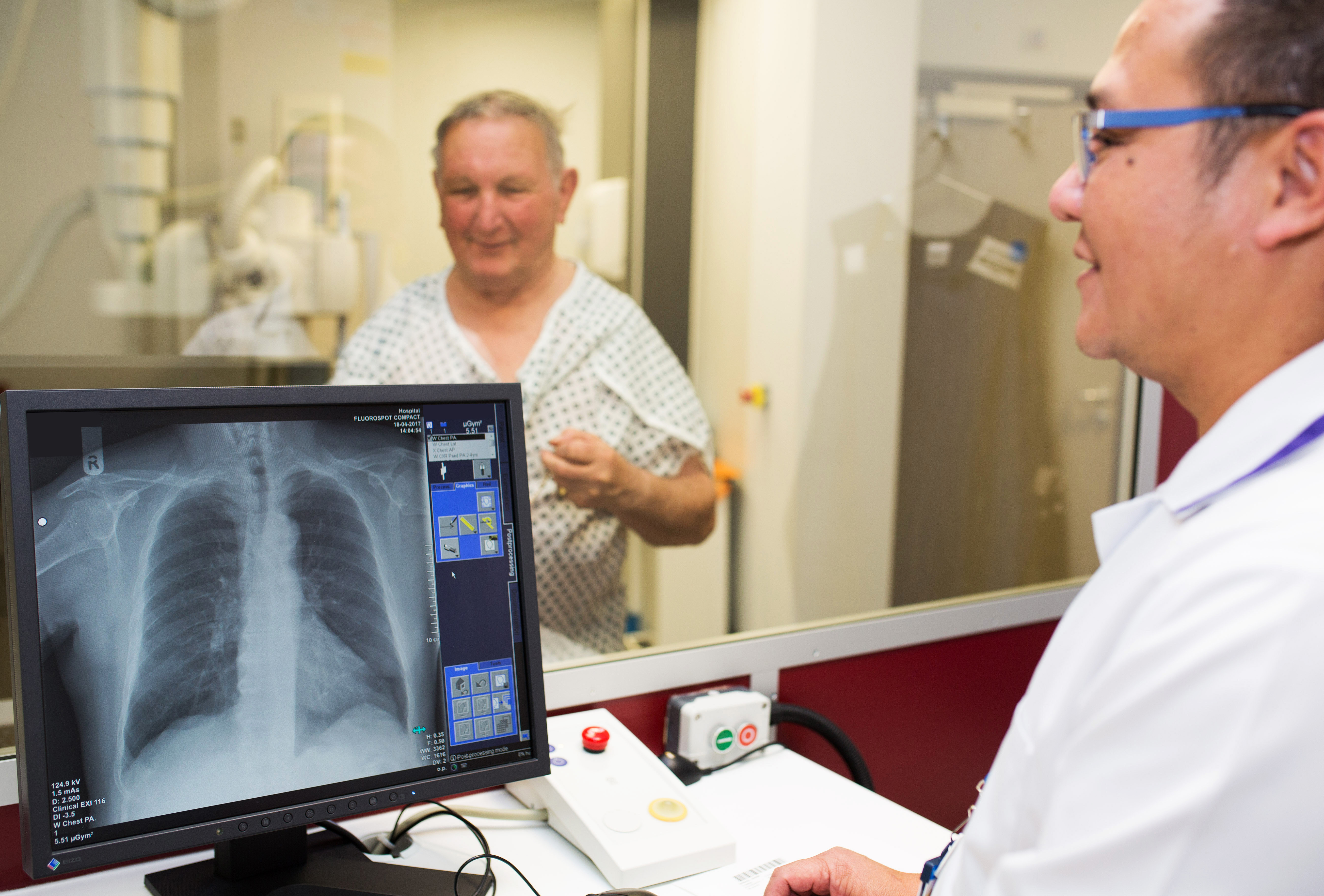 Man having xray, the the foreground you can see the s-ray technician and a picture of the person's chest x-ray