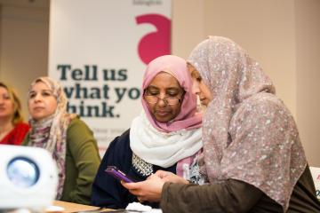 Two women at a Healthwatch event looking at a mobile phone 