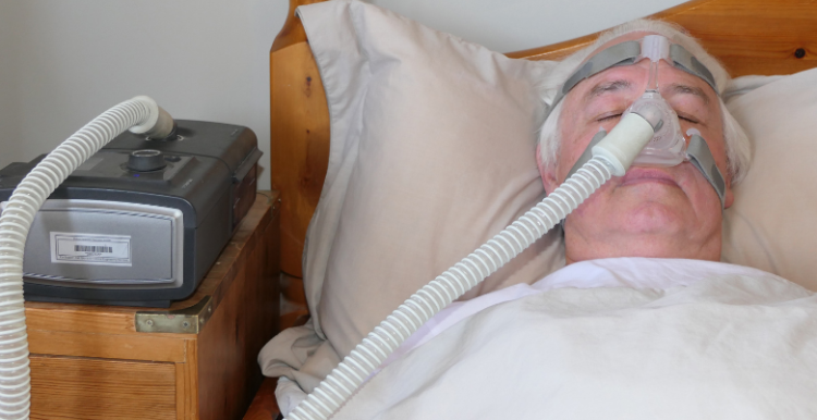 Older man in bed using a CPAP machine to help with his breathing