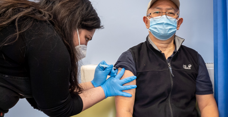 A man receiving a covid jab from a nurse