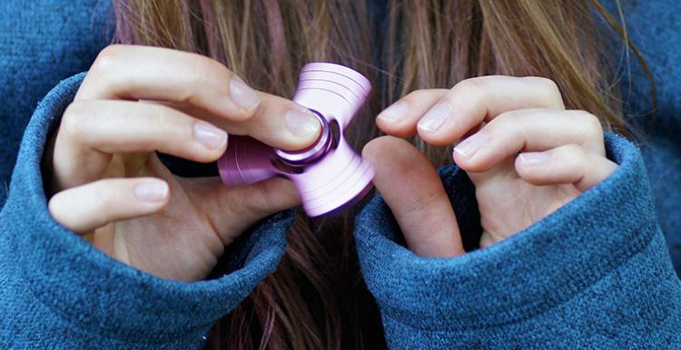 person's hands playing with fidget spinner