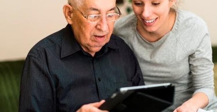 young woman and older man looking at tablet screen