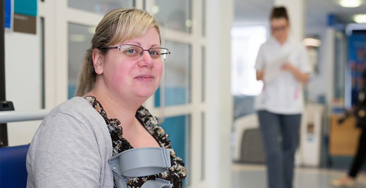 woman waiting in hospital corridor holding crutches