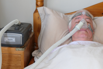 Older man in bed using a CPAP machine to help with his breathing