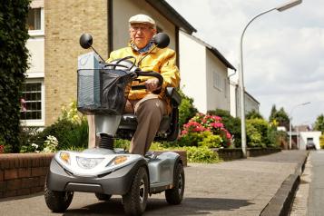 A man using a mobility scooter on a pavement