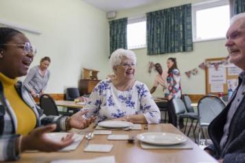 a photo of people laughing and smiling around a dinner table