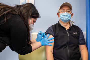 A man receiving a covid jab from a nurse