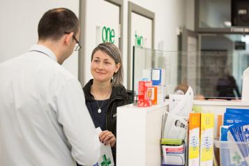 Woman picking up a prescription at chemist's