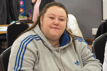 Young woman in grey hoody at Healthwatch event looks at camera