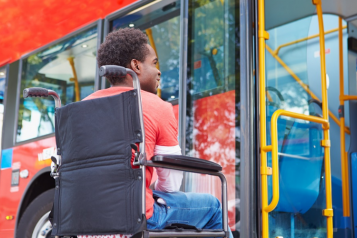 man in wheelchair waiting to board a bus