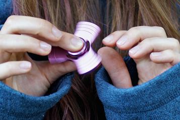 person's hands playing with fidget spinner