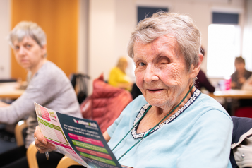 older woman holding a flyer 