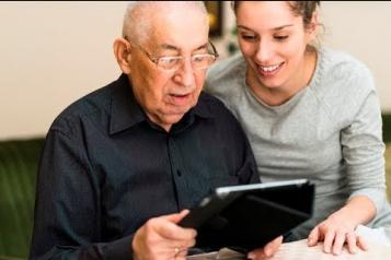 young woman and older man looking at tablet screen