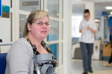 woman waiting in hospital corridor holding crutches