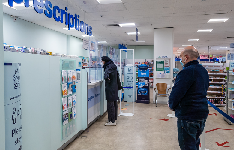 People queuing in a pharmacy to collect prescriptions