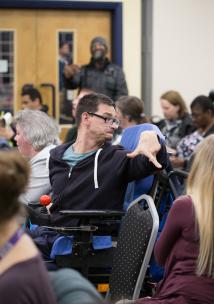 Shows man in wheelchair looking back over his shoulder