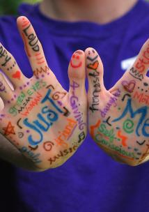 Picture shows words and designs painted on young person's hand 